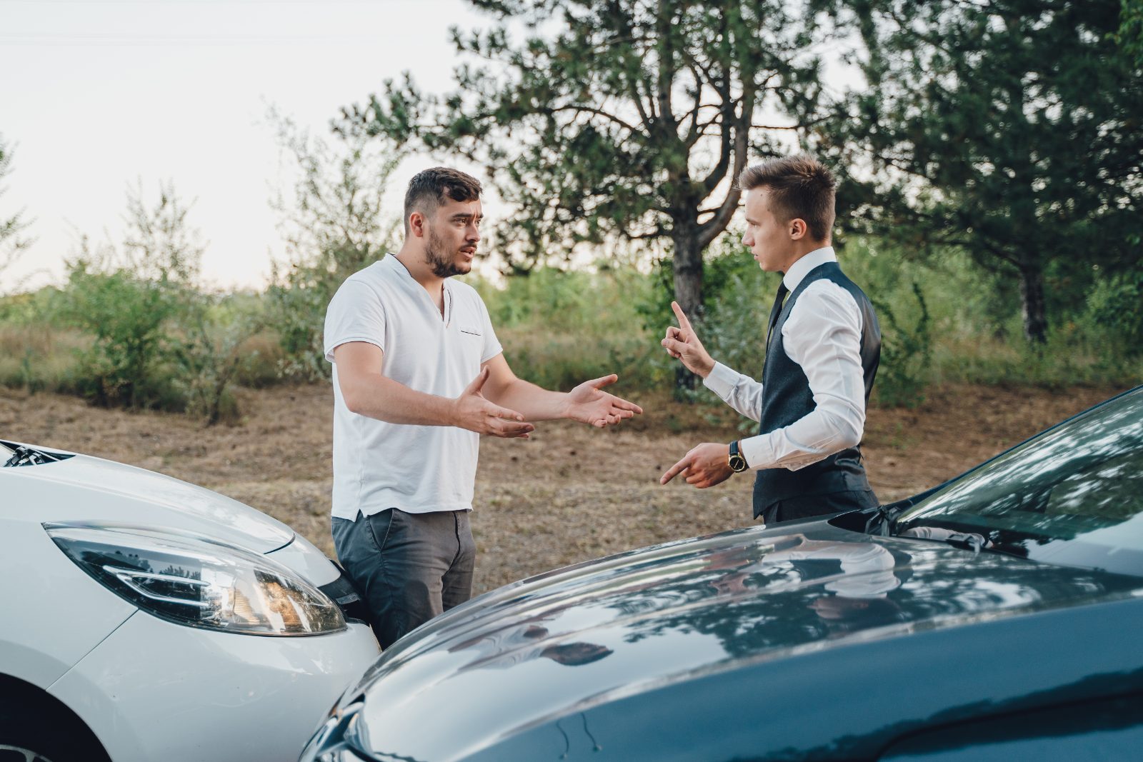 Two drivers arguing beside their damaged cars after a collision