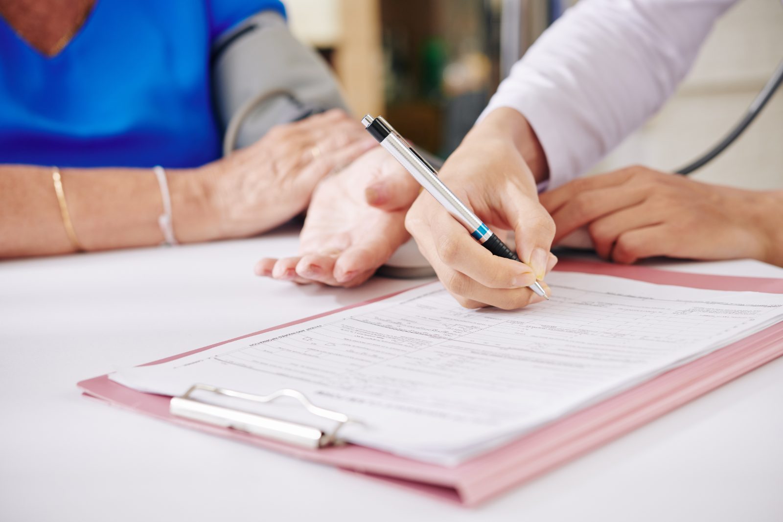 Patient signing a medical form on a clipboard at a doctor's office